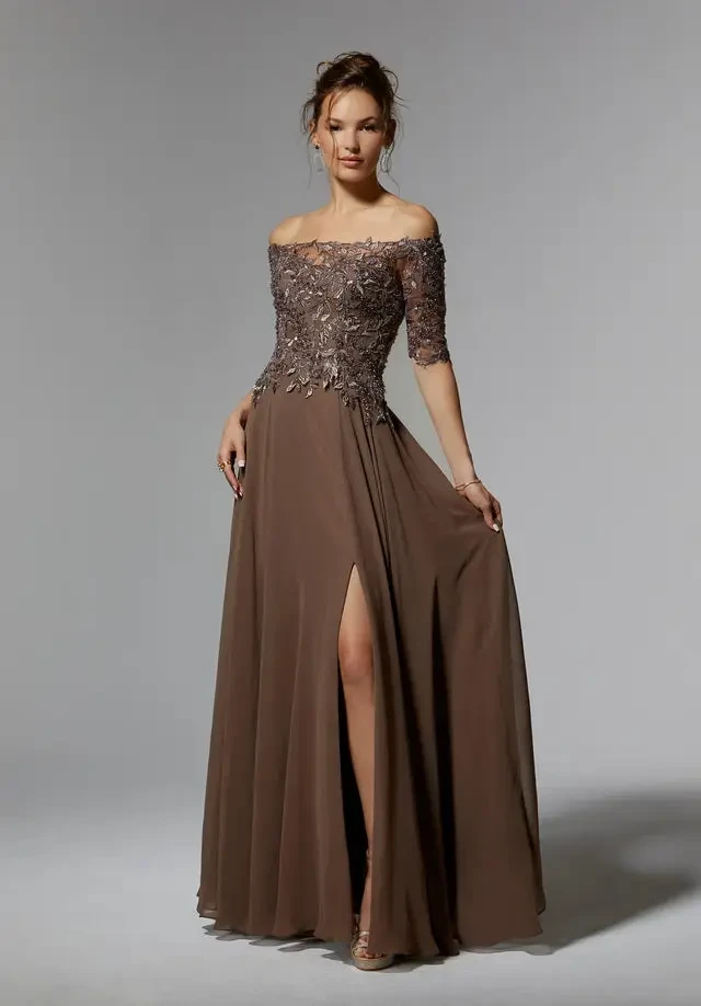 A woman in an elegant brown evening gown with off-the-shoulder sleeves and a thigh-high slit.