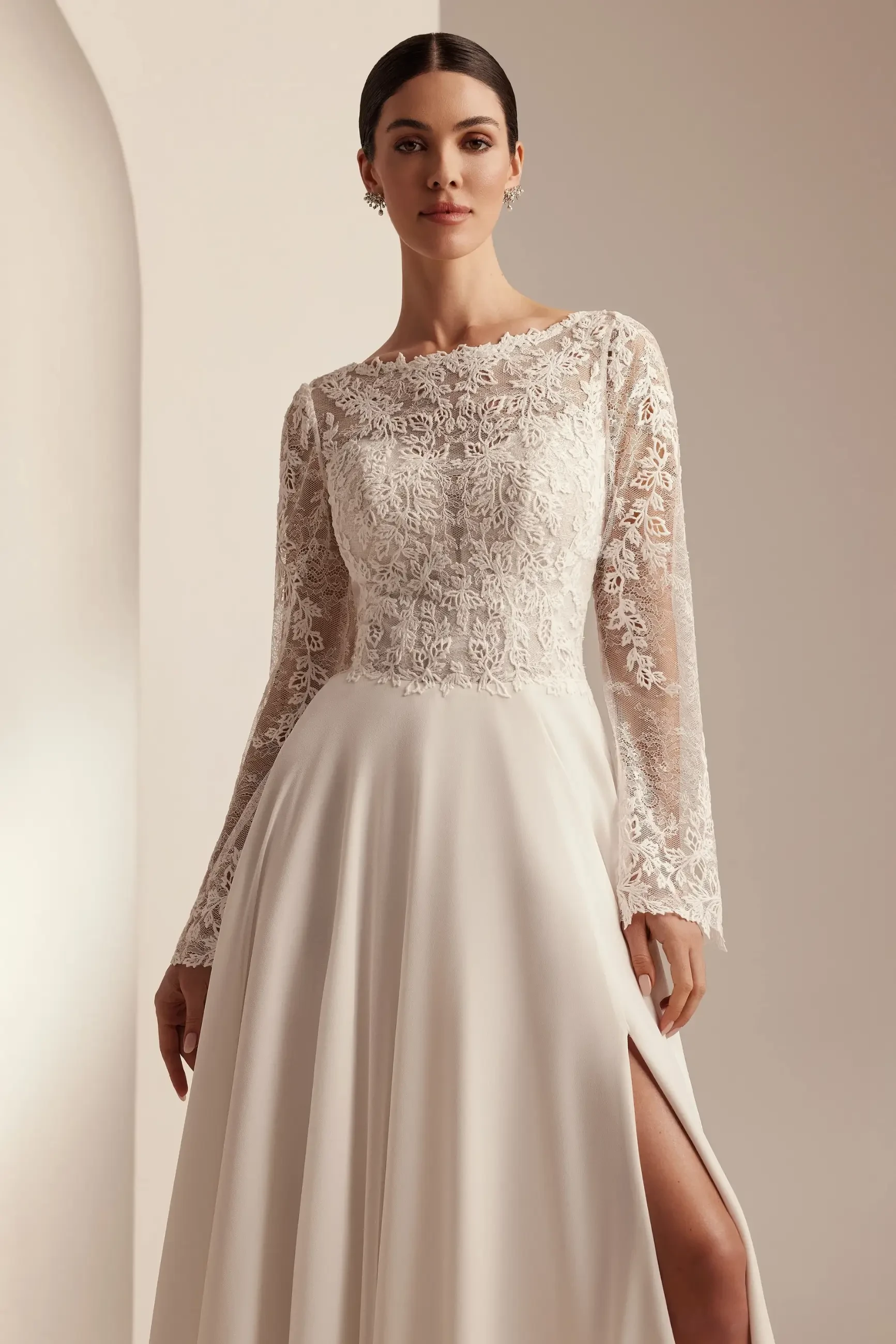 model is wearing a long sleeve a-line lace wedding dress with a high scoop neckline
