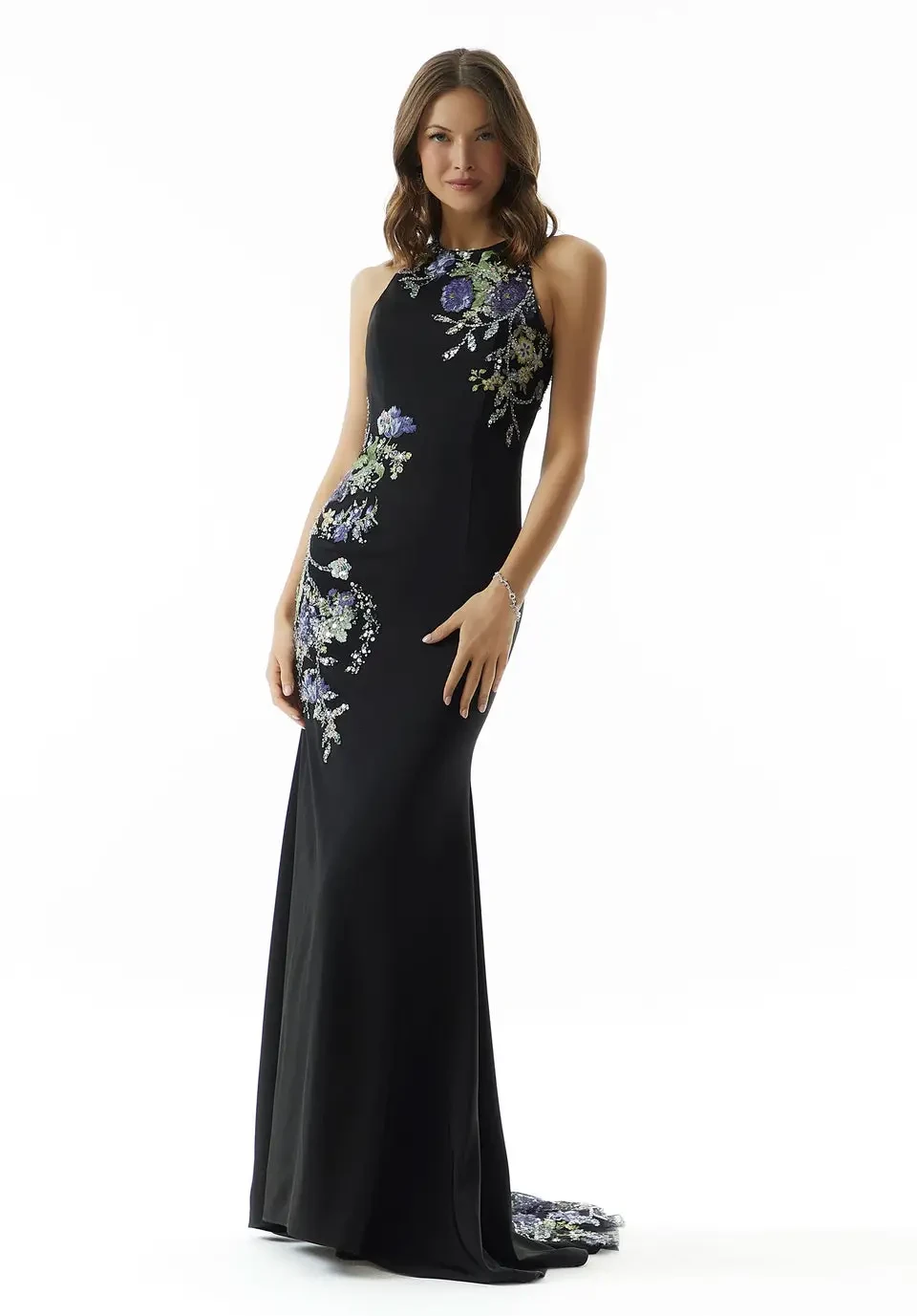 A model wearing a black dress with floral embroidery on one side, posing against a white background.