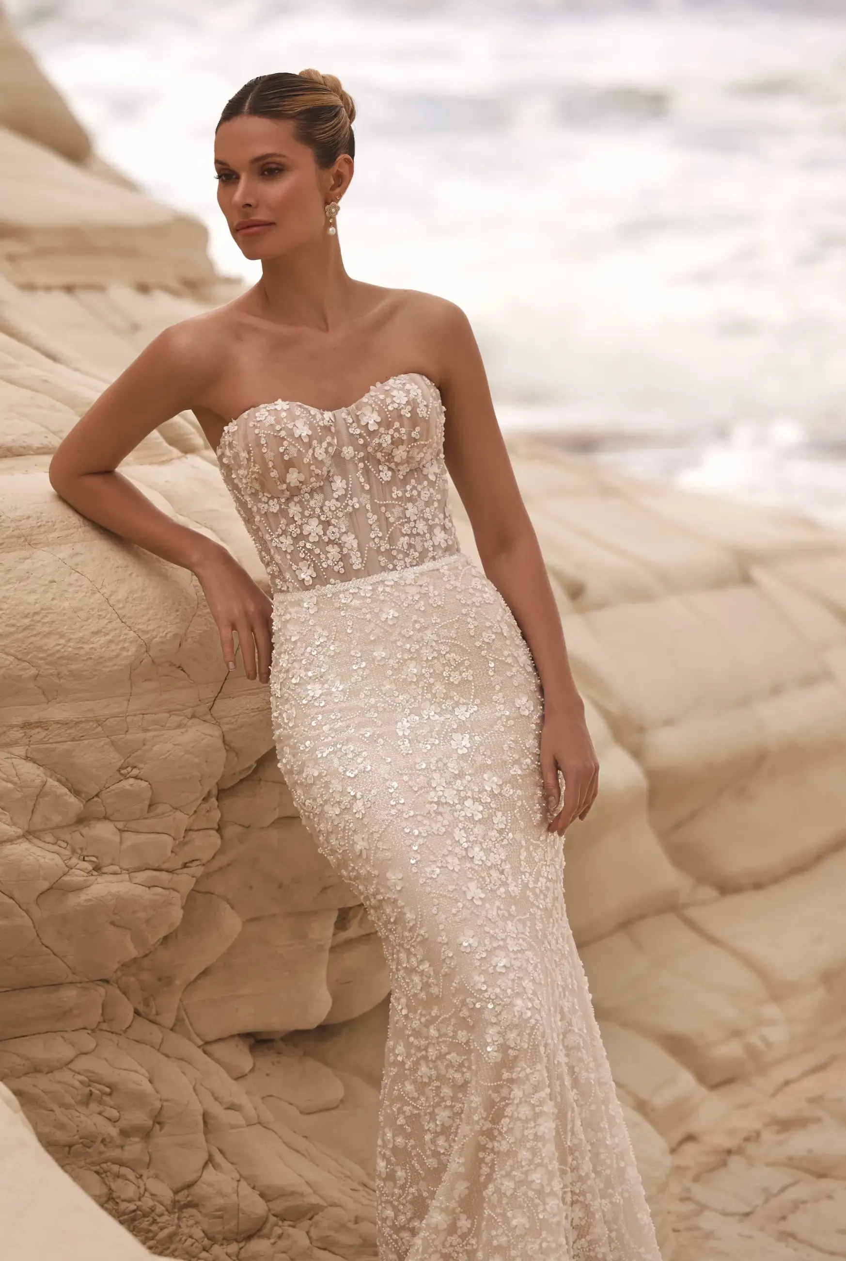 model is wearing a strapless beaded sheath wedding dress